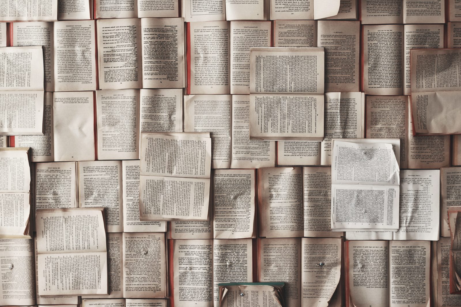 A wall of open books laid edge to edge, pages facing out.